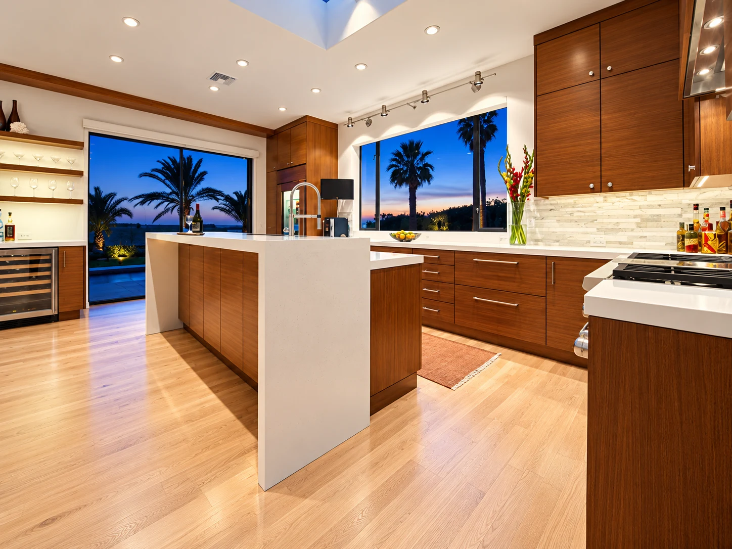 Contemporary wood kitchen with an island and palm trees at dusk